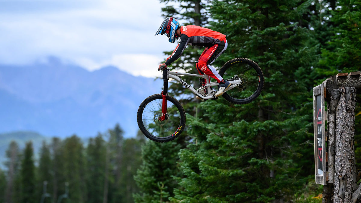 A rider in red in the air at Purgatory, the mountains behind