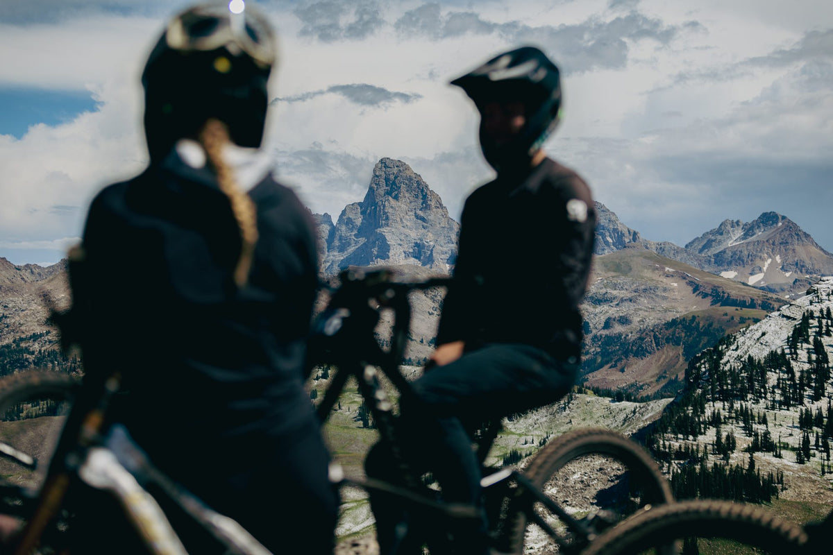 Two riders look out at the Grand Tetons from the top of Grand Targhee