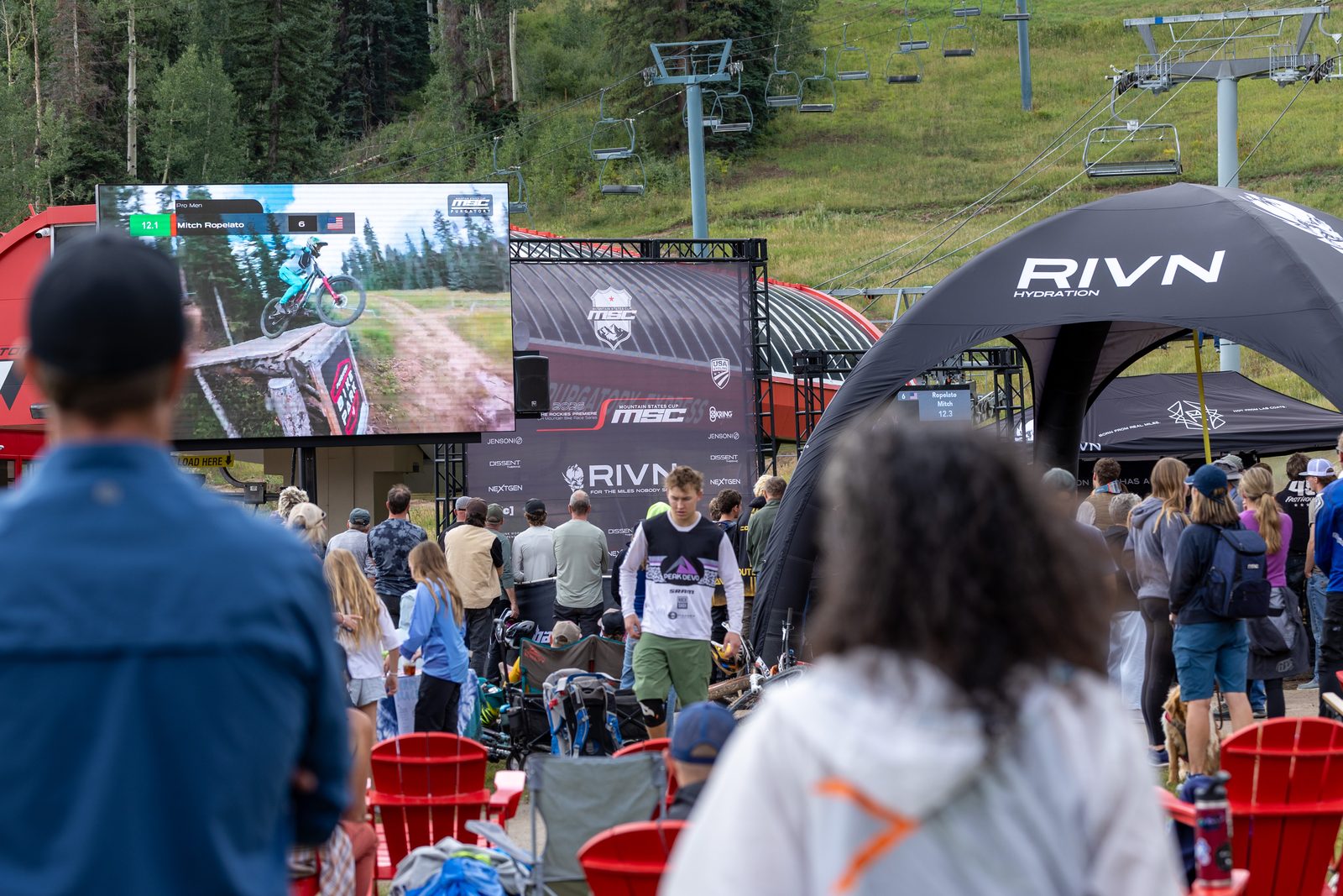 The crowd at Purgatory watching the big screen between runs, a rider on the wall mid-run, the RIVN tent and the red chairs